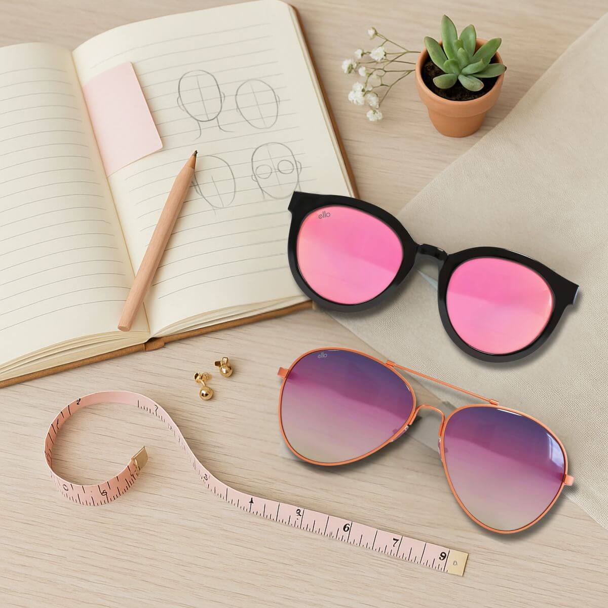 Flat lay of petite sunglasses, measuring tape, and notebook with face sketches for a narrow face sunglasses guide.