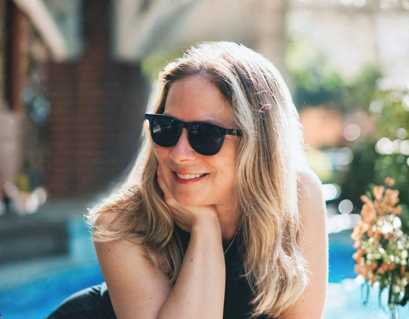 Black grey Outer Banks sunglasses for small faces shown on a smiling woman outdoors in sunlight