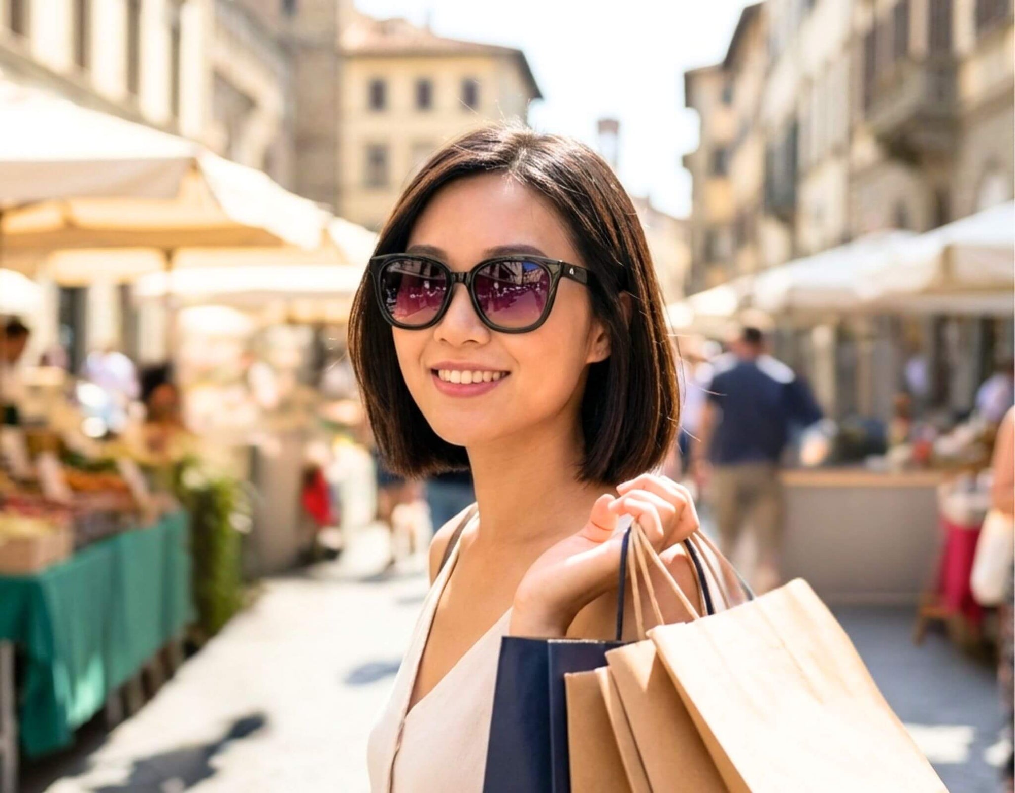 Sunglasses for little faces Pebble Beach in black frame with lavender lenses worn by a woman with a petite face and small head shopping at a sunny outdoor market with ello sunglasses