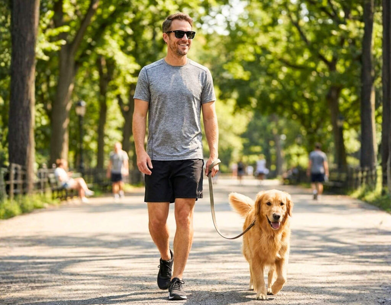 Sunglasses for small faces Outer Banks in black frame with grey lenses worn by a man with a small head walking a dog outdoors in a sunny park with ello sunglasses
