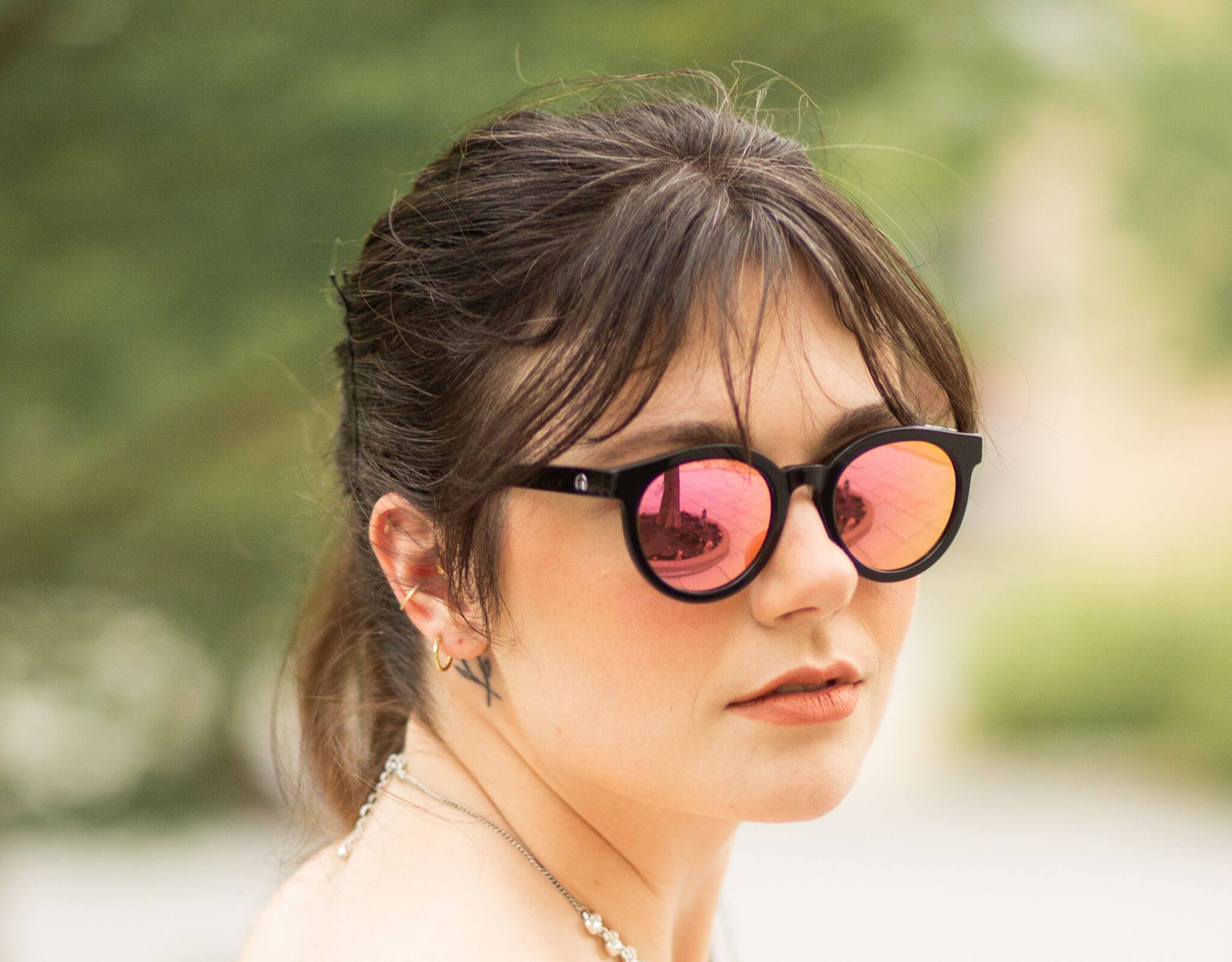 Woman wearing black pink Bar Harbor small sunglasses for small faces, featuring mirrored lenses and soft natural background
