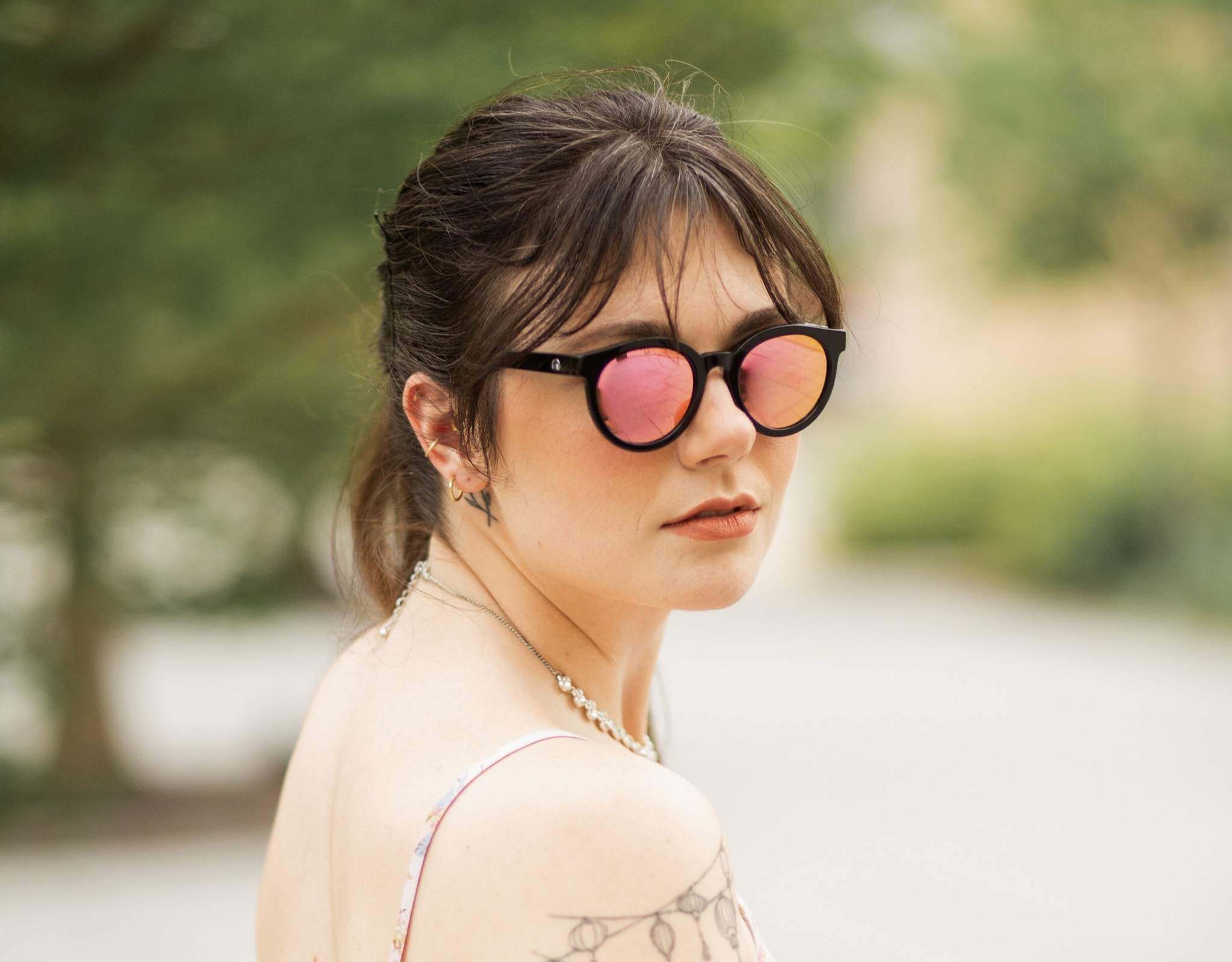 Woman wearing black pink Bar Harbor small sunglasses for small faces, featuring mirrored lenses and soft natural background