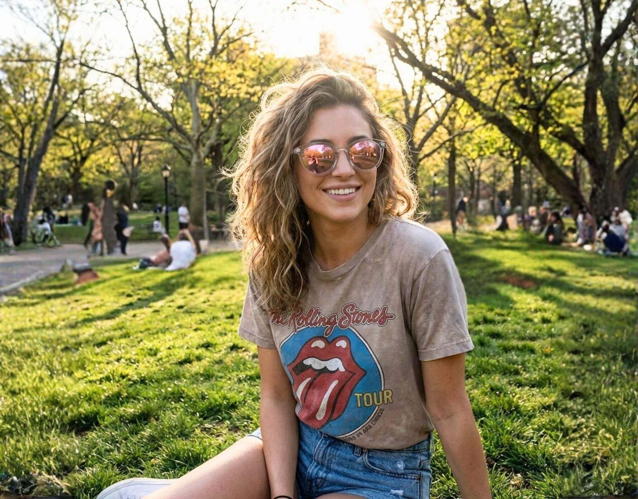 Small sunglasses for small faces worn by woman in Bar Harbor clear frame with purple lenses sitting in park, perfect for petite features and small head by ello sunglasses