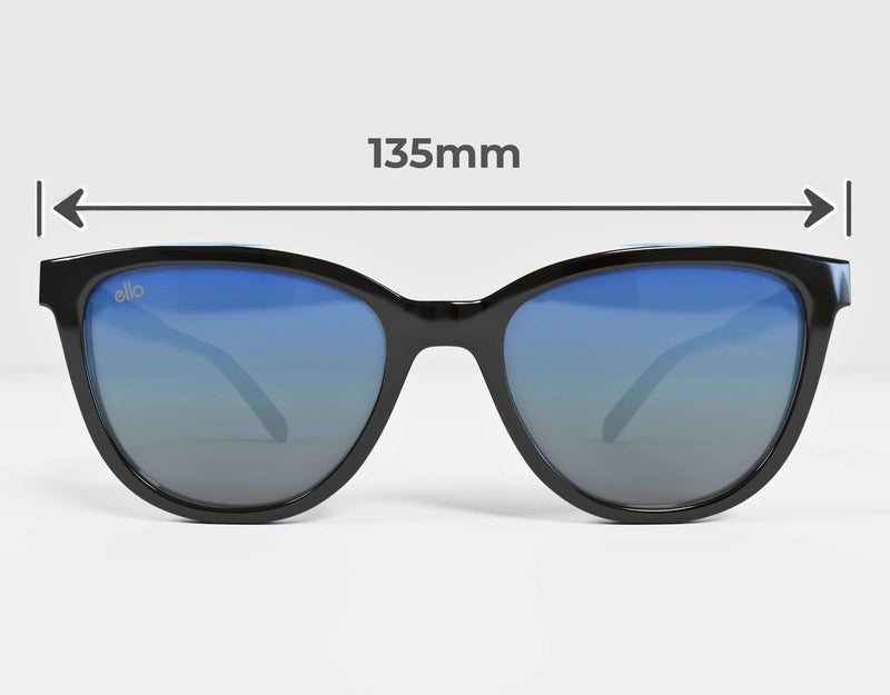 Front-facing view of ello Half Moon Bay black cat eye sunglasses with blue mirrored lenses and measurement arrows showing the 135 mm overall frame width for petite faces.