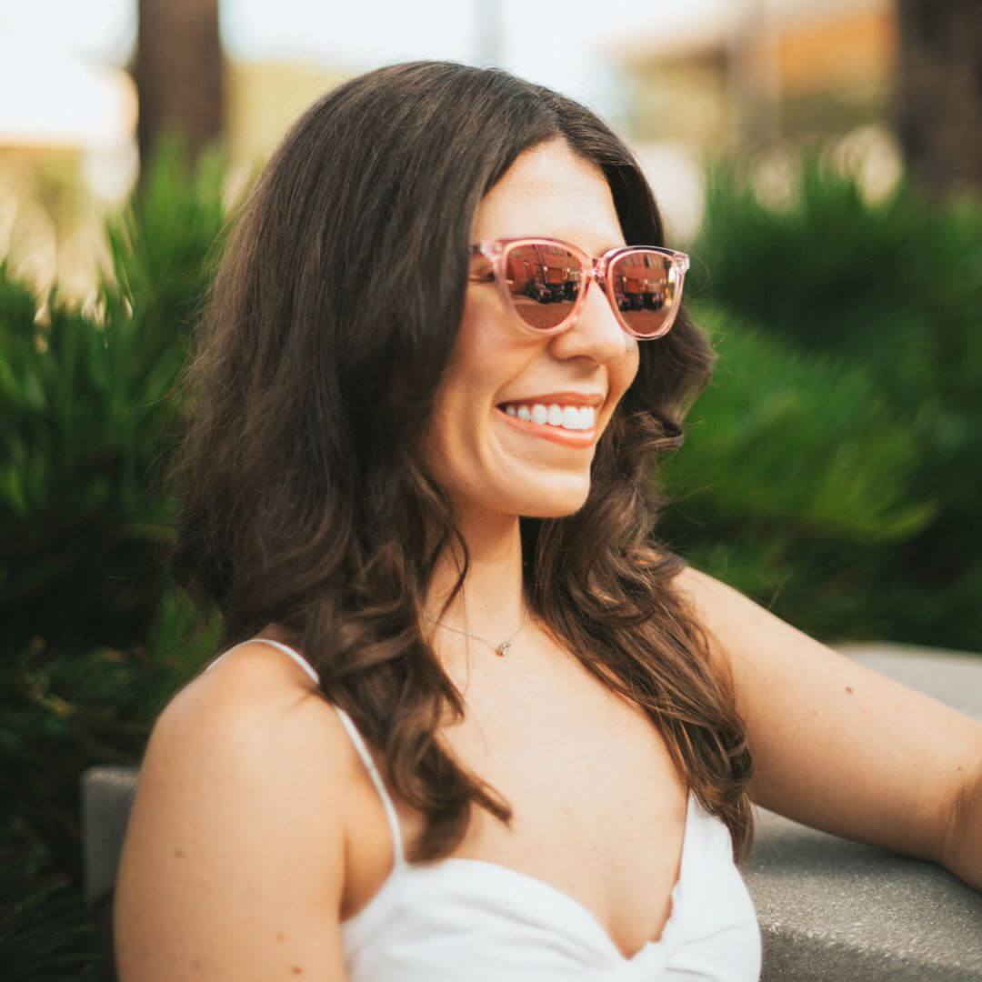 Woman in pink cat-eye sunglasses for petite faces, standing in a garden.