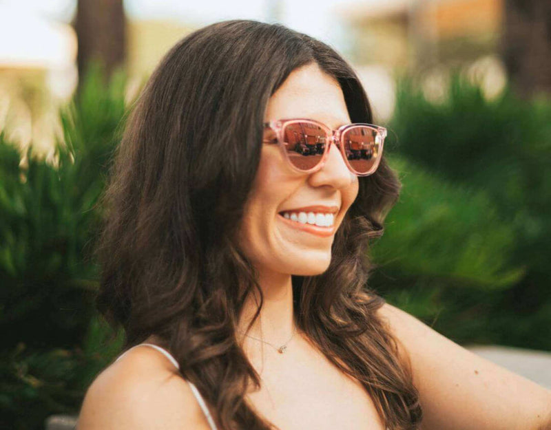 Pink peach Half Moon Bay cat eye sunglasses for smaller faces shown on a smiling woman outdoors in sunlight