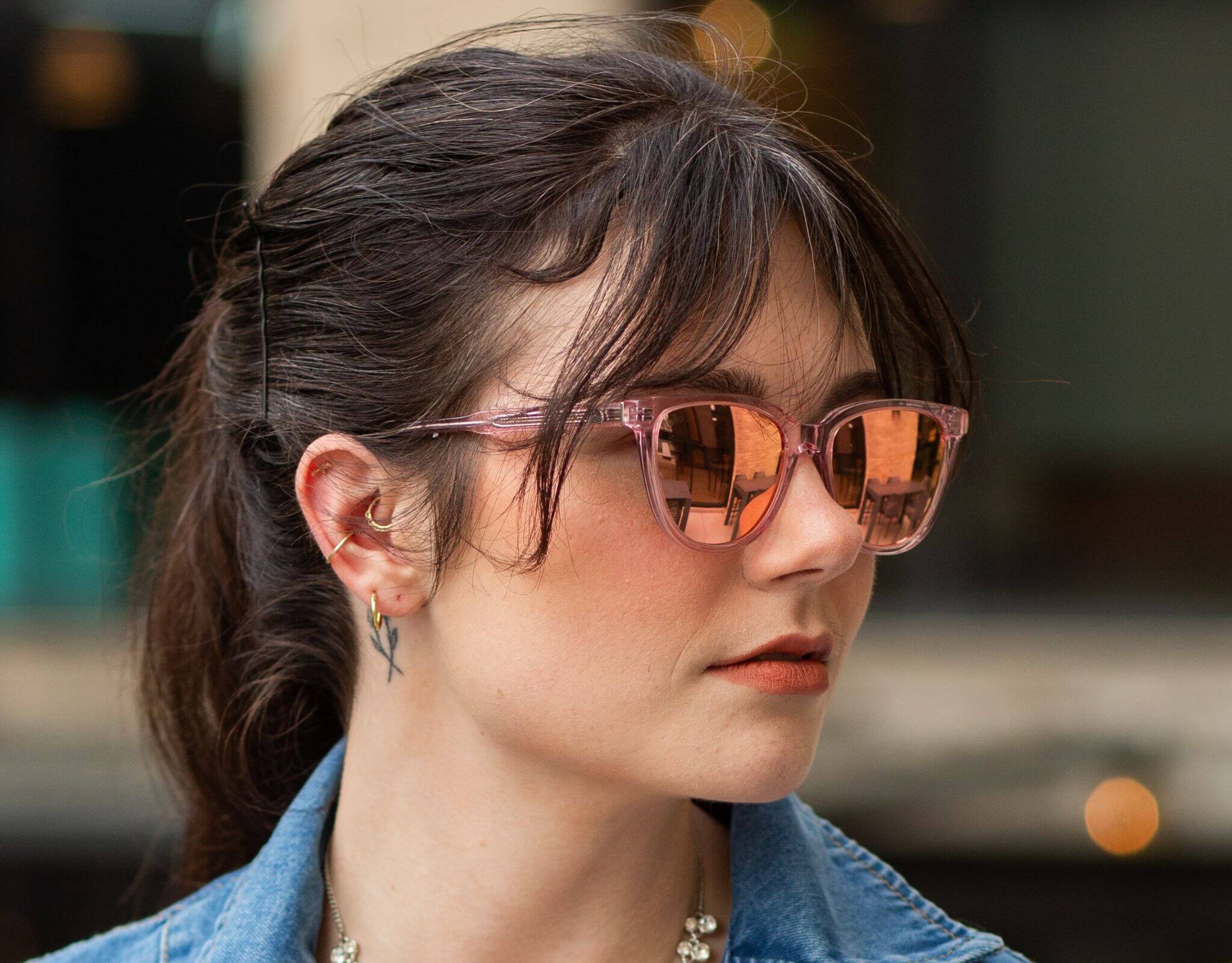 Woman wearing pink peach Half Moon Bay cat eye sunglasses for smaller faces in a outdoor cafe setting.