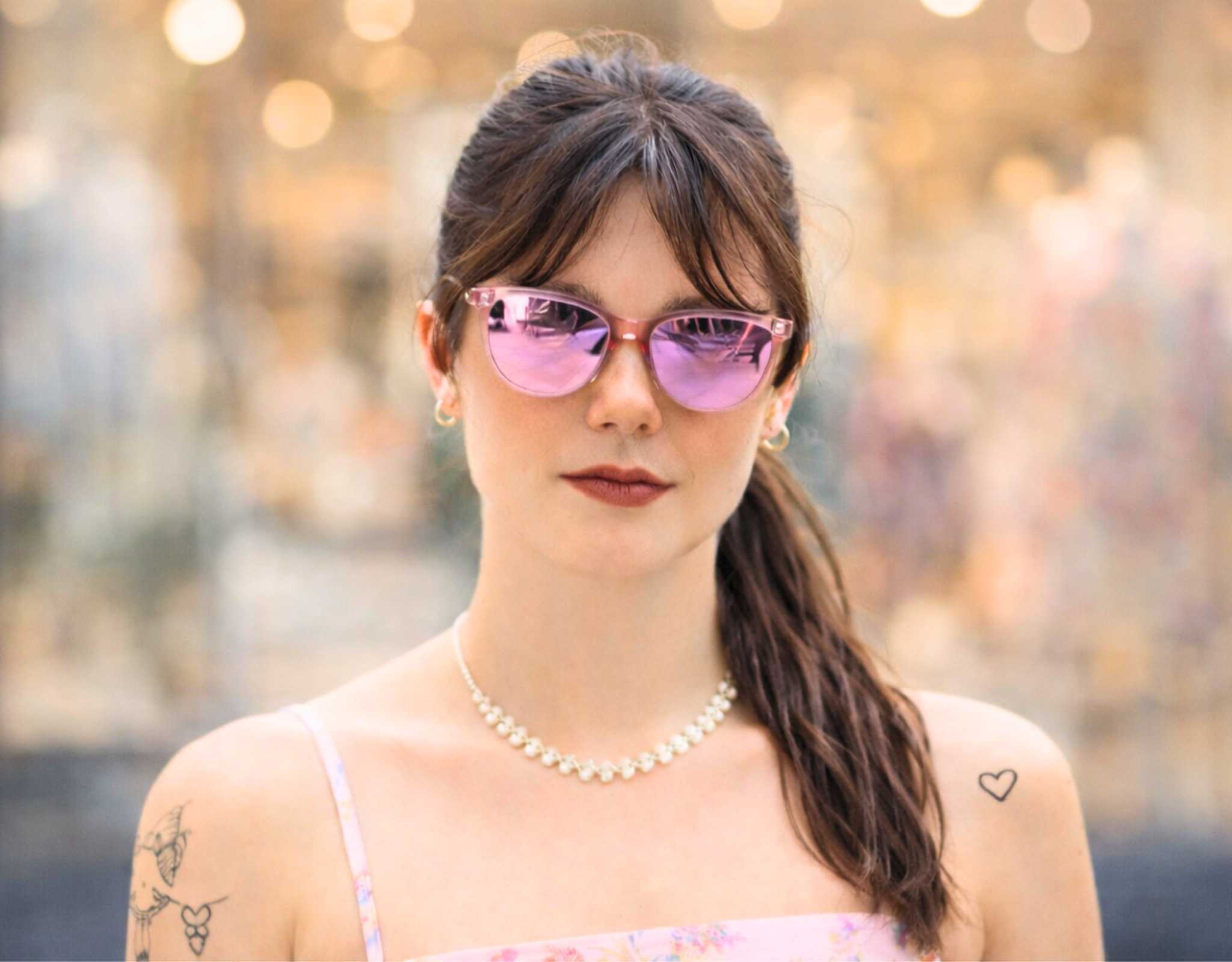 Woman wearing pink Half Moon Bay cat eye sunglasses with purple lenses outdoors, cat eye sunglasses for smaller face and petite features, lightweight polarized summer eyewear