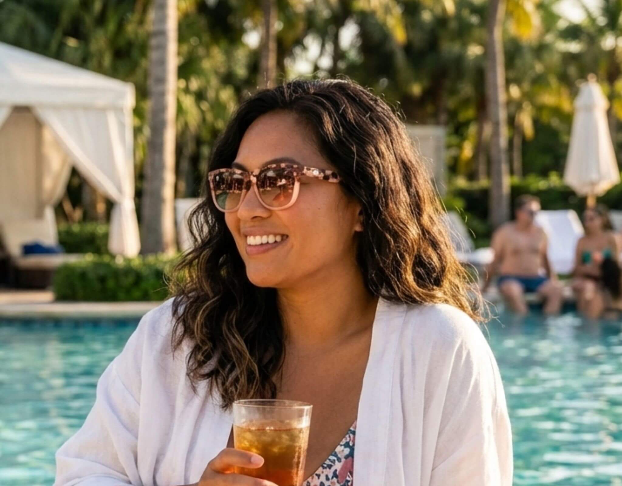 Sunglasses for small faces Outer Banks in tortoise frame with amber lenses worn by a woman with a petite face and small head enjoying a drink poolside in warm sunlight with ello sunglasses