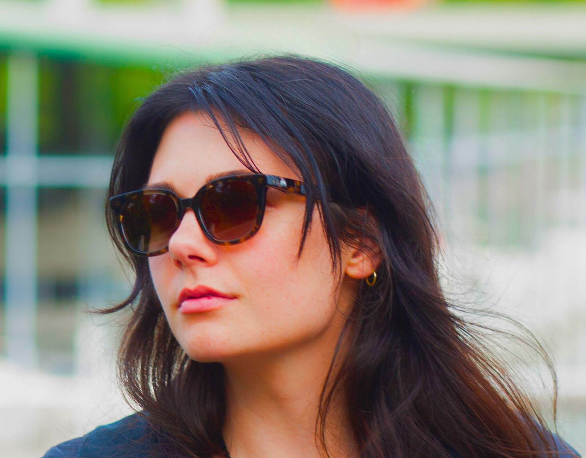 Stylish woman in tortoise amber Pebble Beach sunglasses for little faces with windswept hair and a confident look.