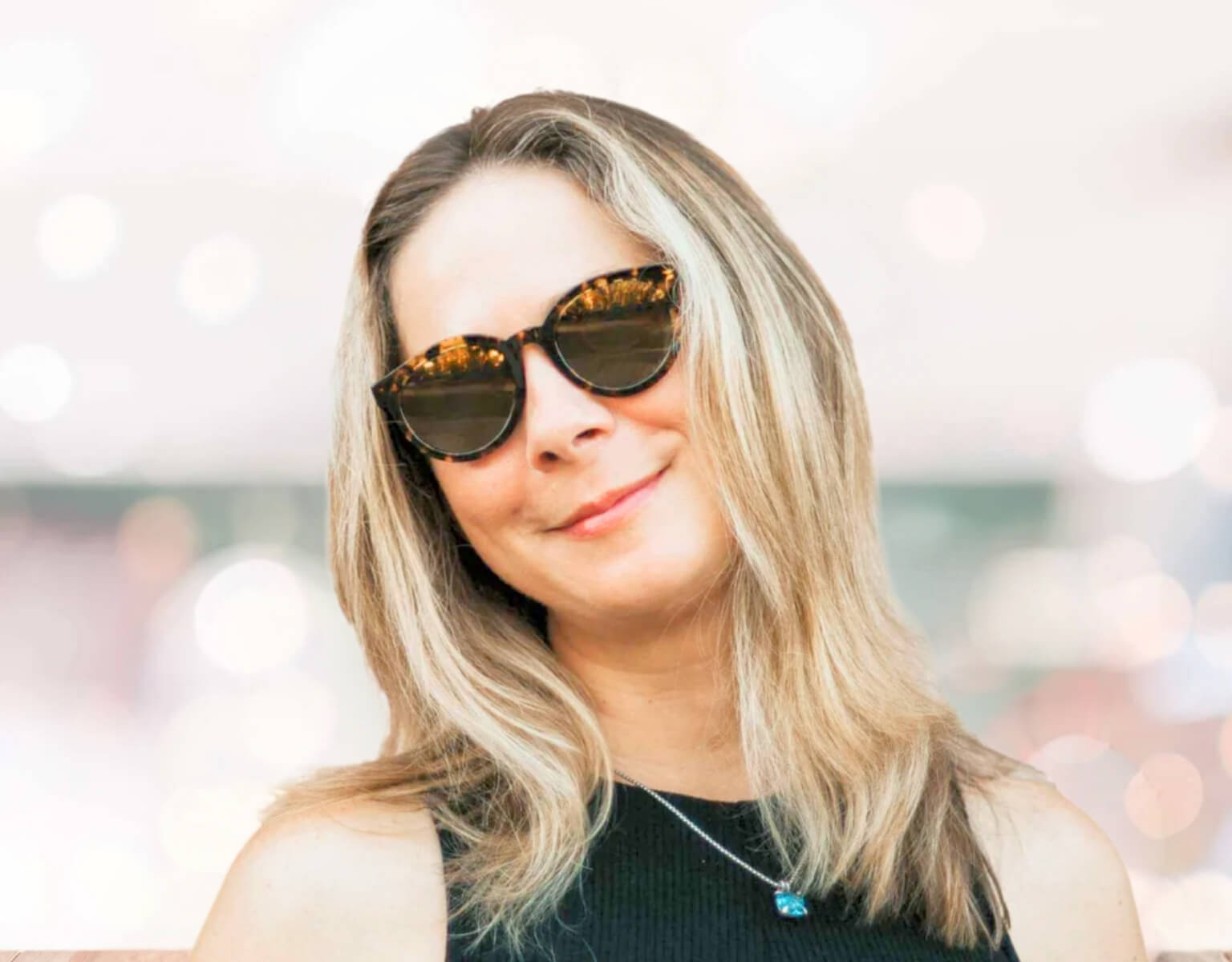 Young, confident woman wearing tortoise gold Bar Harbor small sunglasses for small faces outdoors on a sunny day.