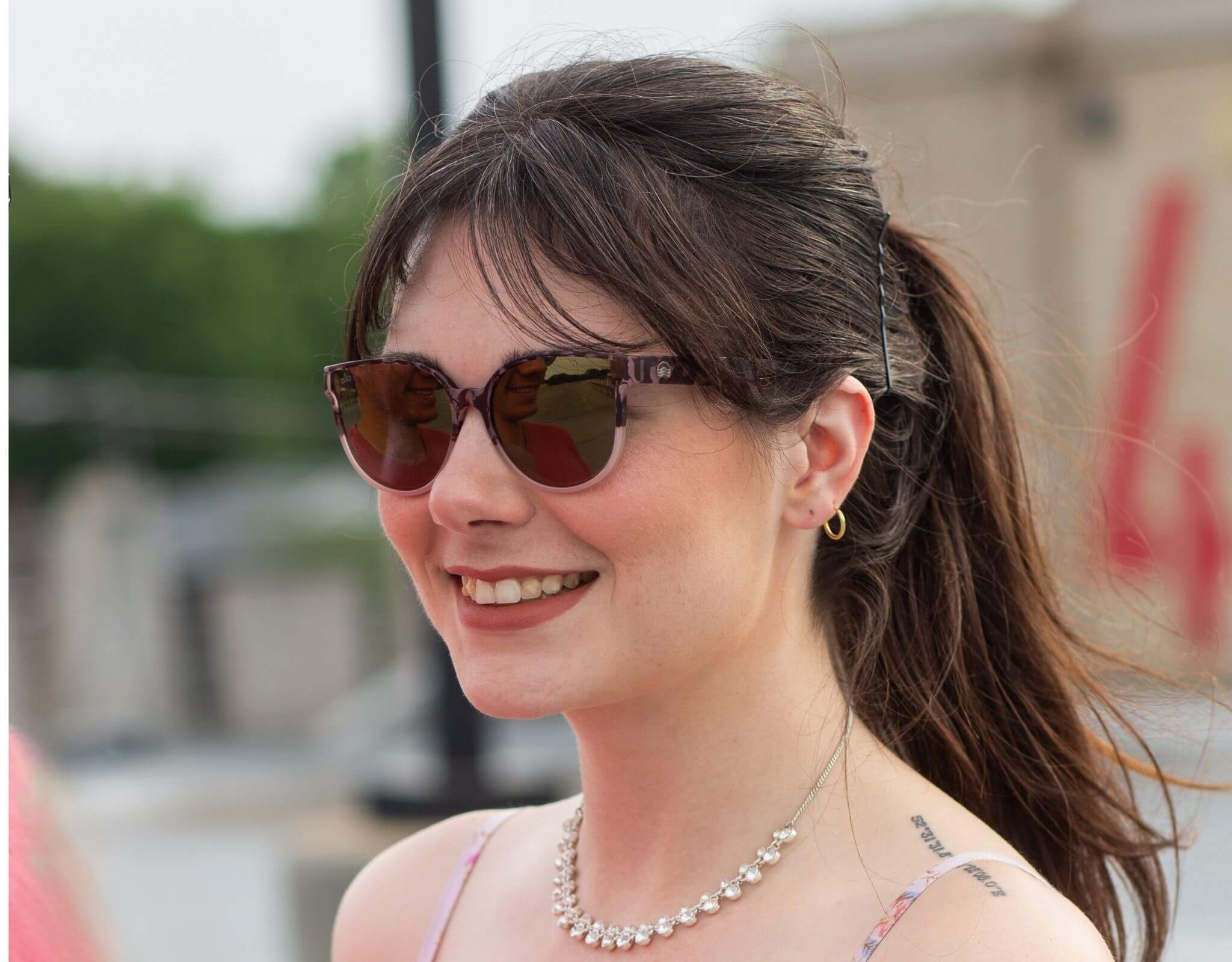 Smiling woman wearing tortoise gold South Beach shades for small faces with hair tied back on a sunny day.