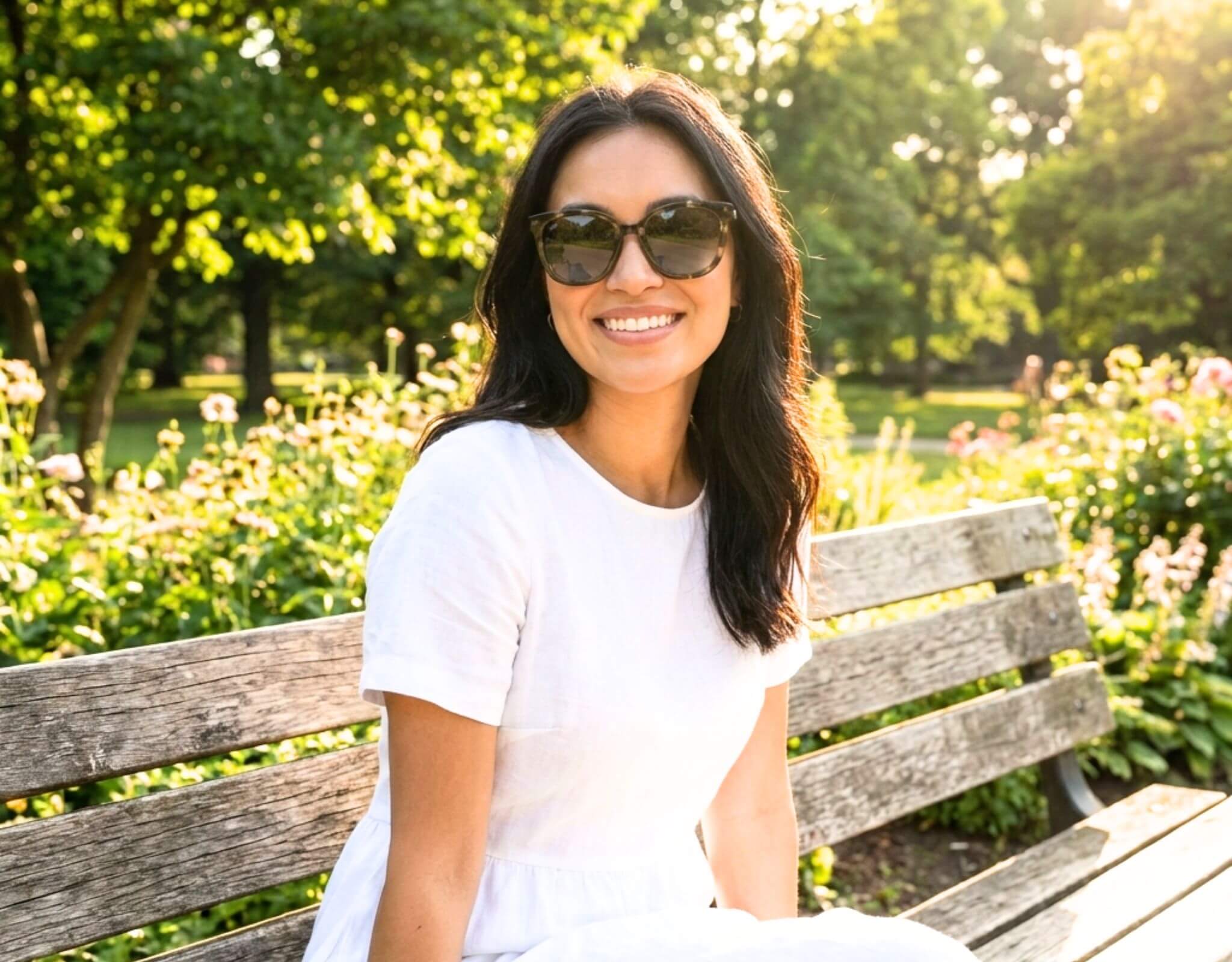 Woman wearing Pebble Beach sunglasses for little faces in tortoise grey with a petite face and small head sitting on a park bench in warm sunlight with ello sunglasses