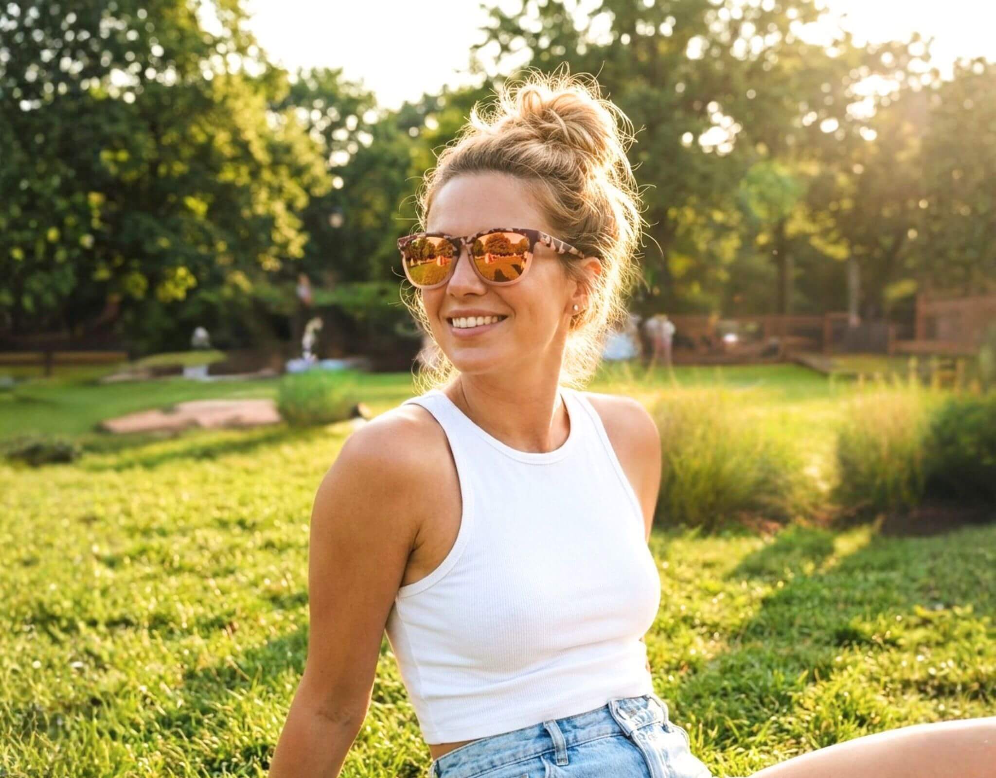 Sunglasses for small faces Outer Banks in tortoise frame with peach lenses worn by a woman with a petite face and small head relaxing in a sunny park with ello sunglasses